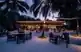 Dining in Maldives with stunning sunset and serene beach waves at a luxury resort.
