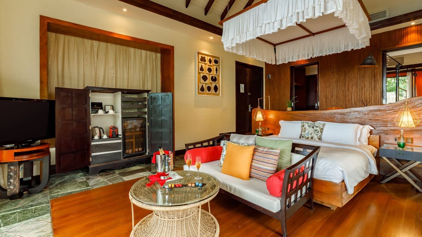 Cozy bedroom with a bed, TV, and wooden ceiling in luxury villas in Maldives.