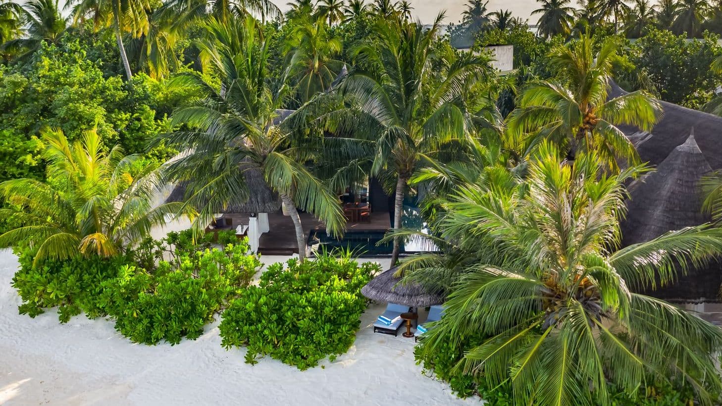 Cozy bedroom with a bed, TV, and wooden ceiling in luxury villas in Maldives.