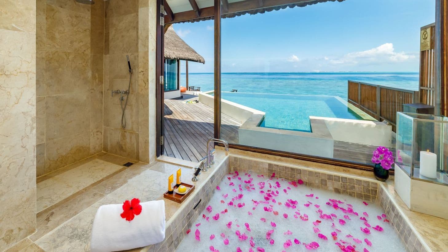 Luxury villas in Maldives with Ocean Pool Suite, tranquil pool and thatched huts under blue sky.