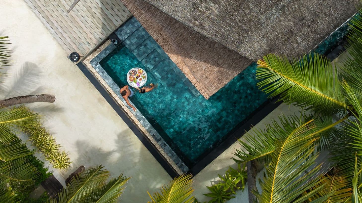 Cozy bedroom with a bed, TV, and wooden ceiling in luxury villas in Maldives.