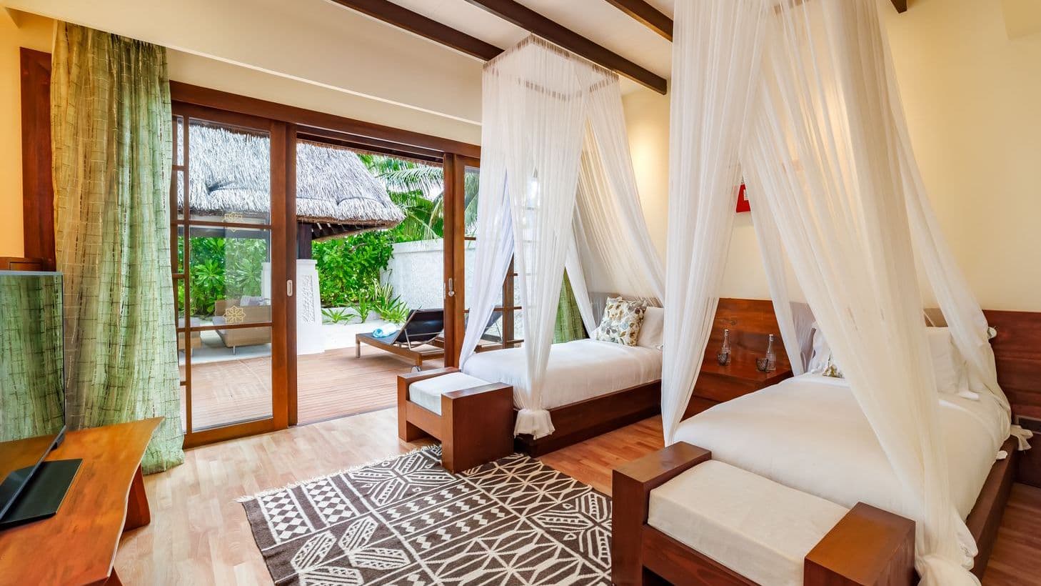 Earth Pool Pavilion 2 Bedroom Suite aerial view of tropical beach with palm trees and clear waters.