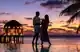 Couple in front of resort at sunset, near vibrant poolside bar and luxury restaurants in Maldives.